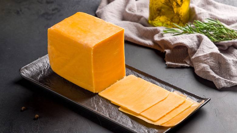 cheddar cheese sliced on black plate on dark table